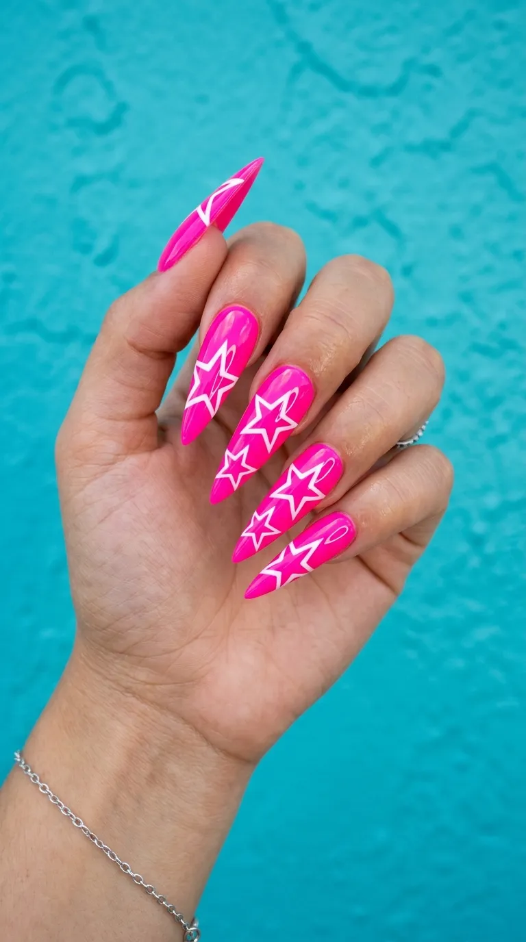 A photograph of long stiletto nails painted in bright neon pink with large white star outlines radiating from the nail bed outward, hand posed against a turquoise blue wall. Bright daylight illuminating the vivid colors. Taken with a DSLR and ring light.
